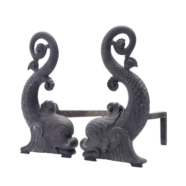 Pair of cast iron dolphin form andirons on iron log rests. The andirons are facing and the log rests are removable and...