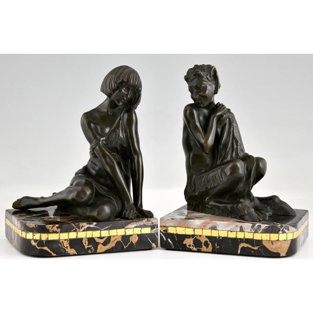 Art Deco bronze bookends nymph and faun by Pierre Le Faguays. Patinated bronze on a Portor marble base with glass inlay....
