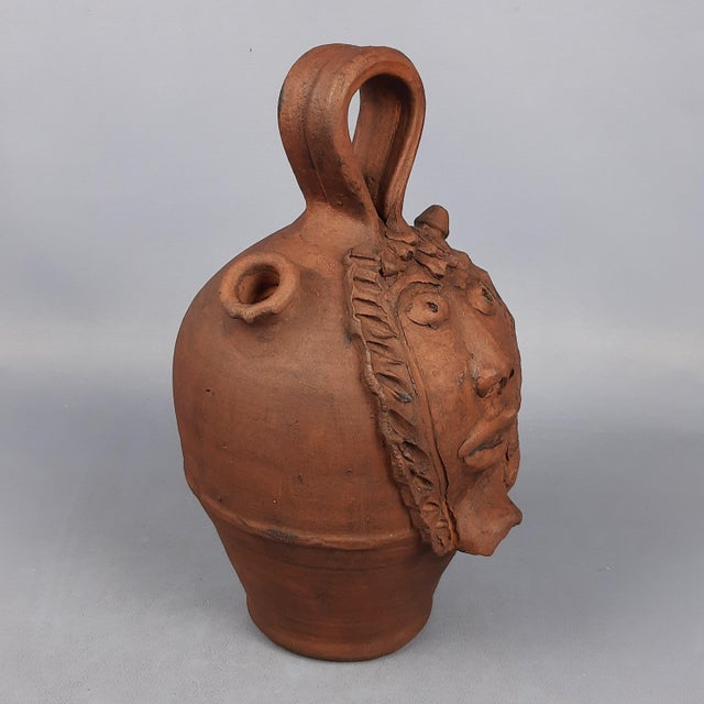 Fantastic vintage collectible jug/flask, made of terracotta and decorated with a human face in relief. The work has marked...