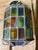 This vintage stained glass pendant lamp features a multicolor paneled design held together by twisted metal trim.