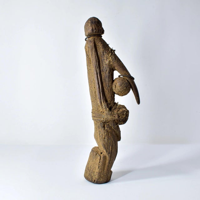 Carved with precision and adorned with raffia, shells, and fabric, the Dogon Abstract Fetish Figure Knife reflects the...