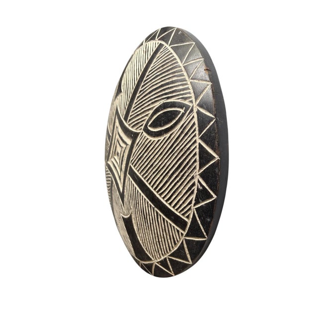 A hand-carved shield from the Bamileke people of Cameroon, hand carved from a single piece of wood. This striking round...