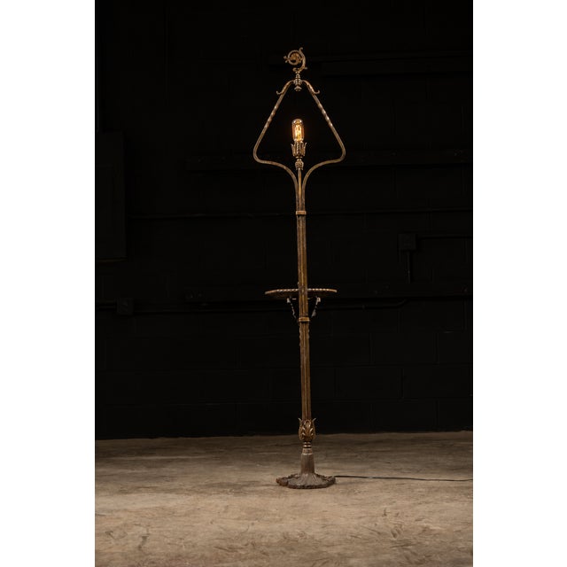 Ornate brass lamp with what appears to be the head of a crozier on top and an attached ashtray and non-functional, built-...