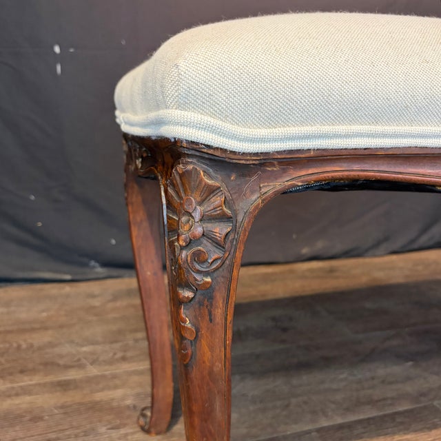 A graceful 19th century French Louis XV bench crafted in richly figured walnut, featuring hand-carved shell and floral...