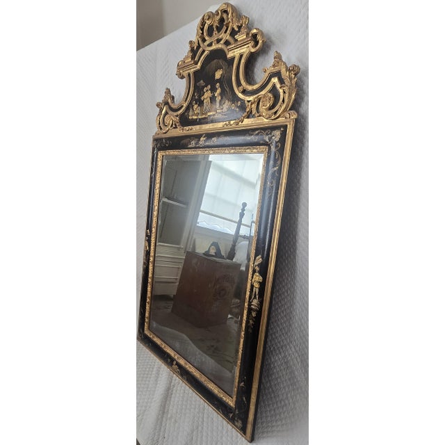 Striking 19th century wall mirror with a black lacquered frame richly decorated with gilt chinoiserie scenes and an...