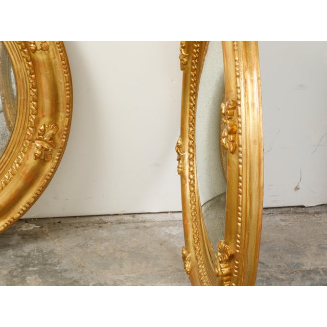 A pair of English giltwood convex mirrors from the mid 20th century, with carved acorns and foliage motifs. Created in...