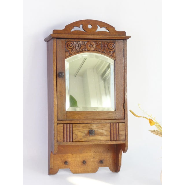 Antique small wooden cabinet with an arched shaped beveled mirror in the front door. The medicine cabinet is adorned by...