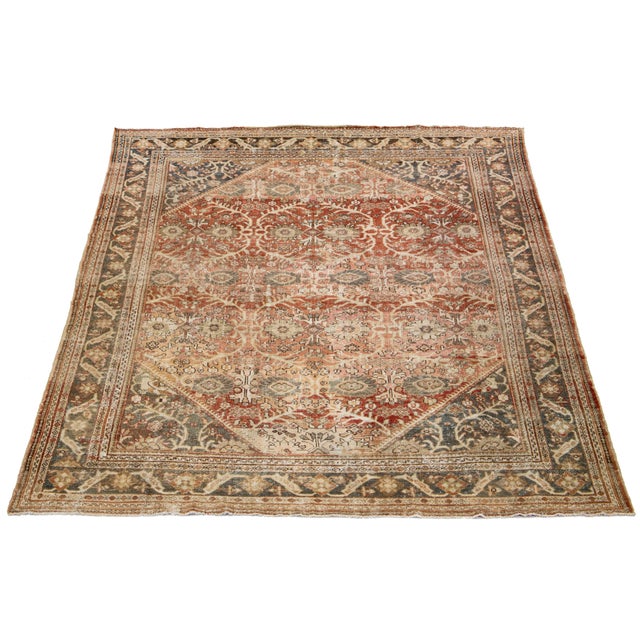 Hand-knotted wool Persian rug with rust field and floral motif in blue, pink, and brown hues. This rug measures 9'10" x...