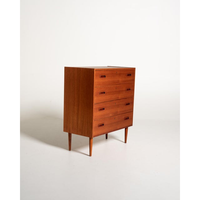 Scandinavian teak chest of drawers from the 1960s, featuring four large drawers and double recessed handles. The frame is...