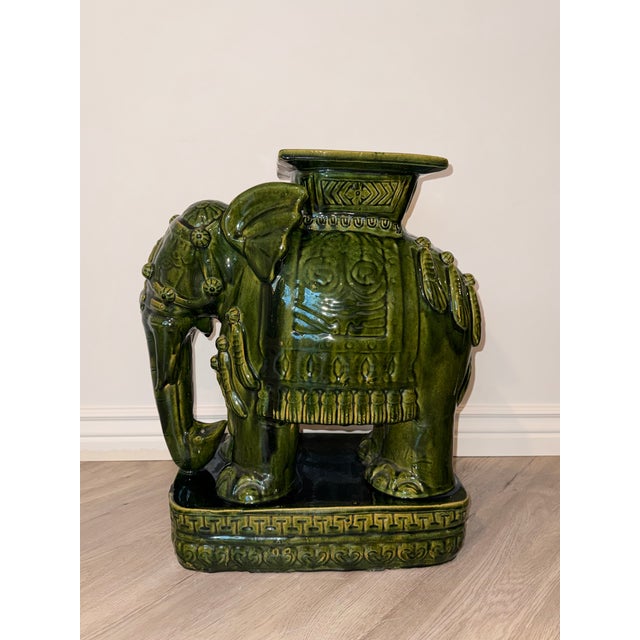 Striking pair of emerald green glazed ceramic elephant plant stands in the Hollywood Regency style. Each elephant features...