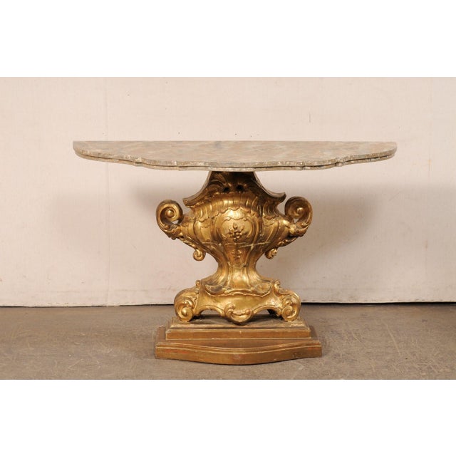 An Italian carved-wood pedestal console table, in urn motif, from the 18th/19th century. This antique table from Italy is...