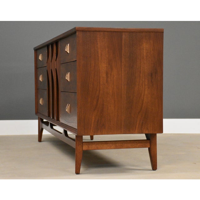 A mid century modern walnut nine dovetail drawer dresser with polished brass drawer pulls made by Broyhill Brasilia....