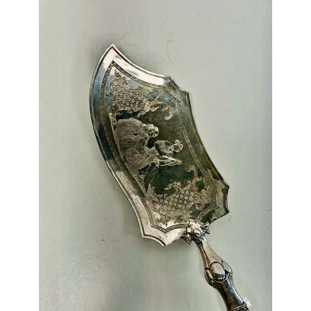 Intricately hand-engraved figural and floral motifs adorn the asymmetrical blade of this server which is mounted on a...