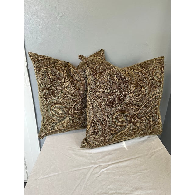 This elegant pair of decorative throw pillows features a rich green, light blue, and brown palette woven into a soft,...