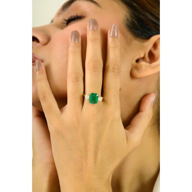 Bold yet elegant, this exquisite ring features a vibrant 2.8-carat octagon-cut emerald at its center, flanked by two...