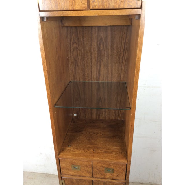 This mid century campaign style wall unit by Stanley Furniture features lighted area with glass shelf, upper cabinet with...