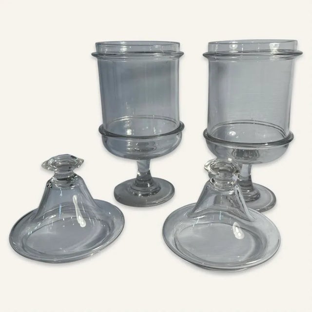 Pair of 19th century Pittsburgh glass jars with lids and feet The lids terminate in a point with a hexagonal finial. The...