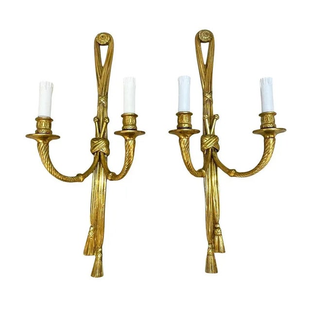Amazing matching pair of gilt bronze sconces in the shape of knotted ribbons holding two candle arms. These amazing set...