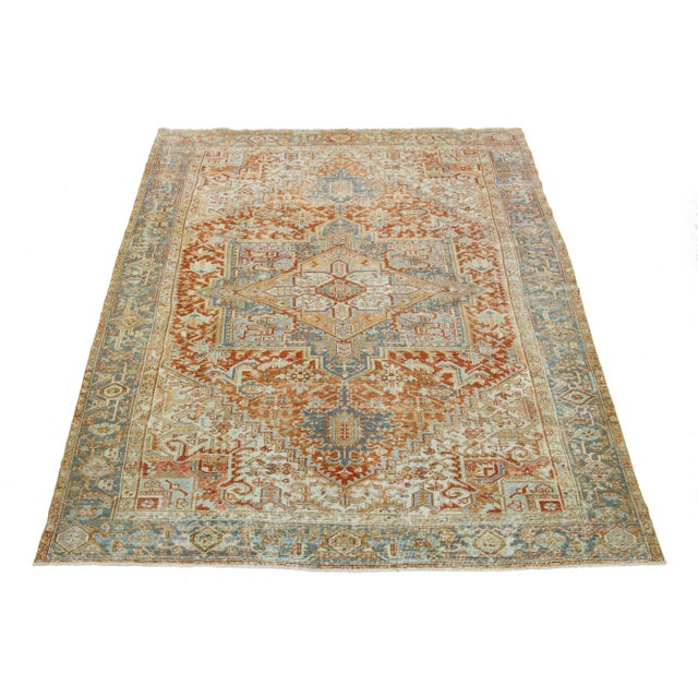 This antique Persian Heriz rug is crafted with hand-knotted wool. The rust-colored field features a captivating medallion...