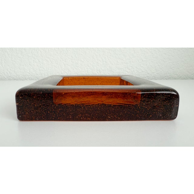 Brutalist style, thick art glass ashtray or catchall in the style of Blenko Glass. It is a deep amber/copper color and...