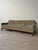 Mid-century sofa with a subtly curved profile, upholstered arms, and an exposed wood base. The frame supports three loose...