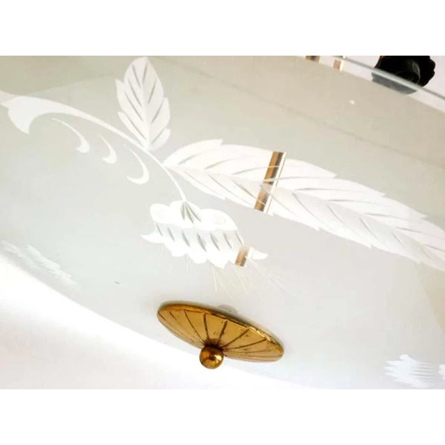 This three-light pendant lamp features a satin-finish curved glass diffuser embossed with floral details and a brass base....