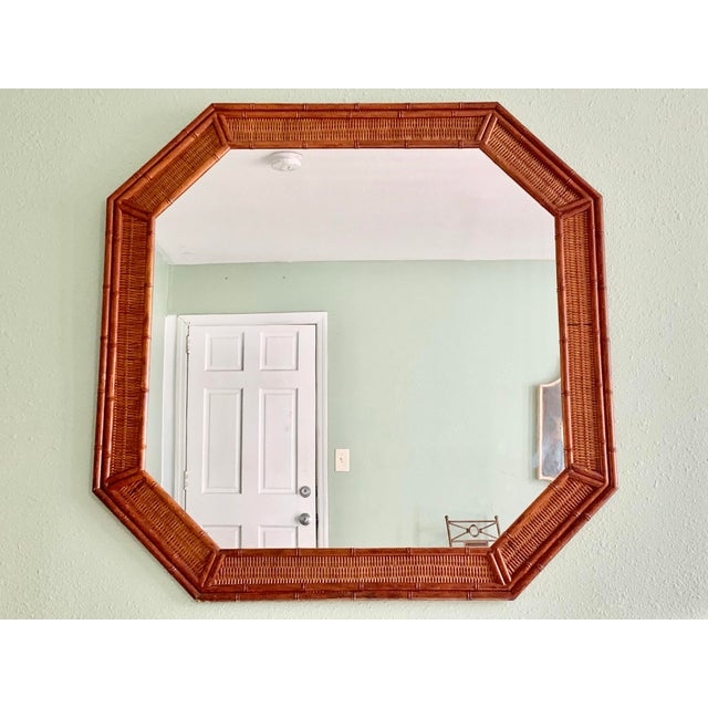 Striking large vintage octagonal wall mirror featuring a faux bamboo frame with woven cane panel insets, embodying the...