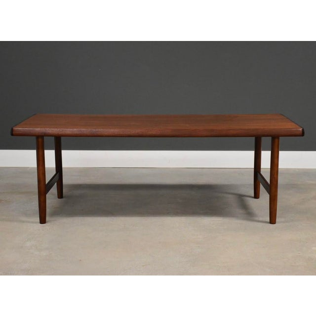A mid century modern tall teak coffee table with simple lines and side stretchers. Unmarked. Made in Denmark....