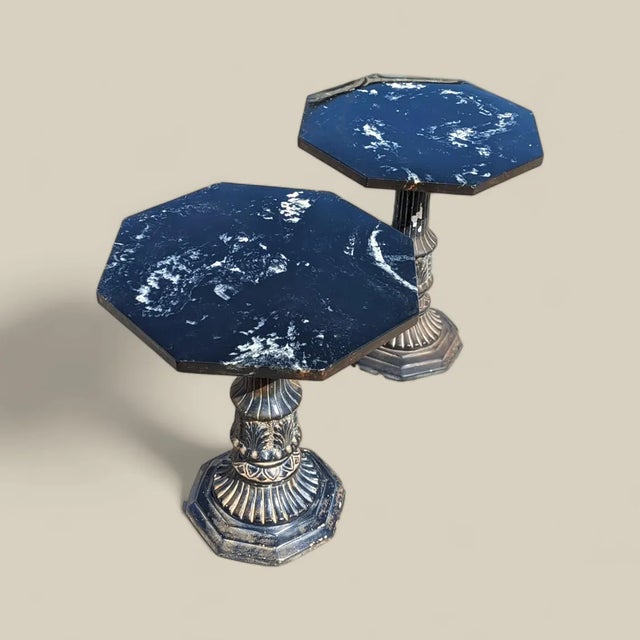 A dramatic pair of vintage pedestal tables combining octagonal black marble tops with richly ornamented architectural...