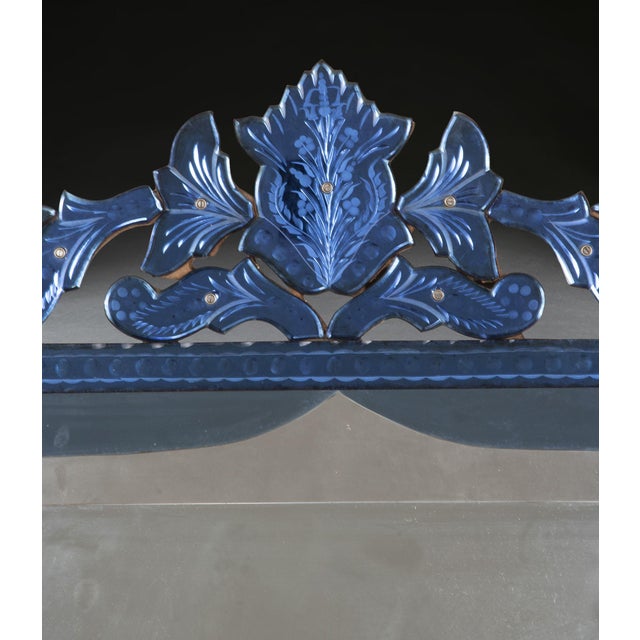 A very decorative late 19th century venetian mirror with blue glass borders, engraved crest and semi elliptical interior...