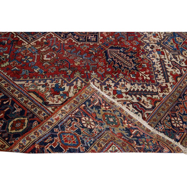 Beautiful antique Heriz hand-knotted wool rug with a red color field. This Persian rug has multicolor accents in a...