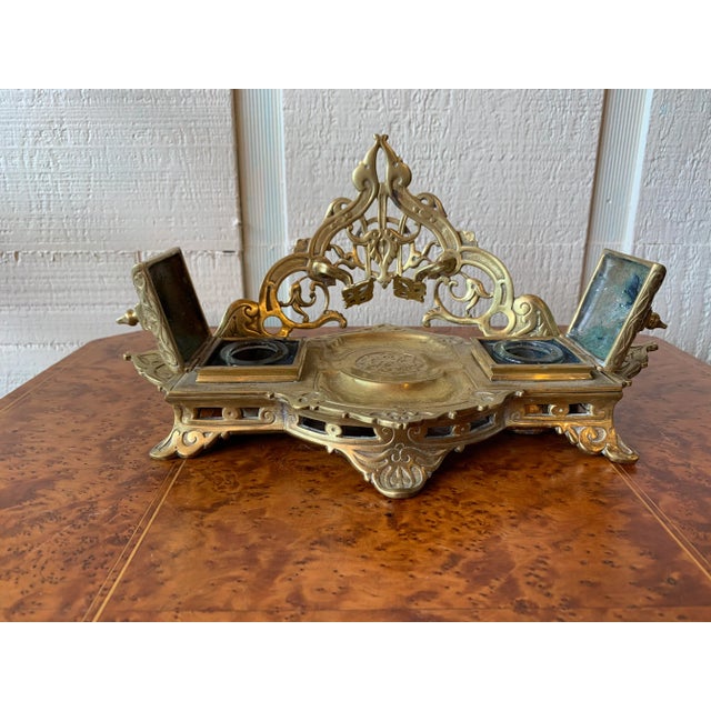 Distinctly tooled and pierced brass inkwell. Pen rest and dual wells. Original glass well liners.