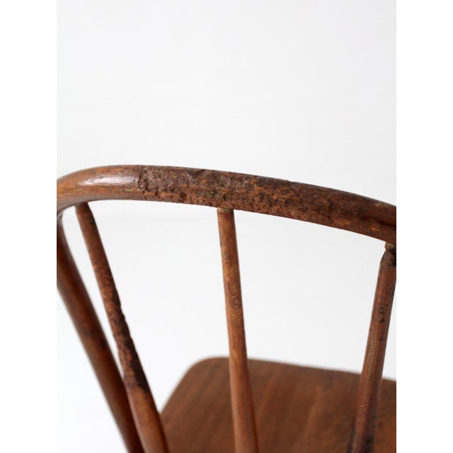 This antique Windsor bow back chair features a continuous curved crest rail, tapered spindles, and turned legs with simple...