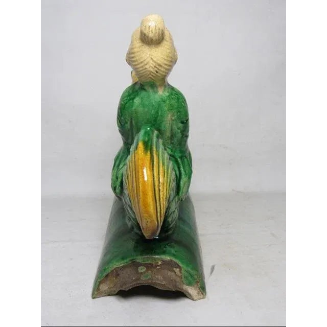 Chinese ceramic roof tile, c.1930’s An end cap tile with a circular motif showing a mythical animal face. A figure riding...