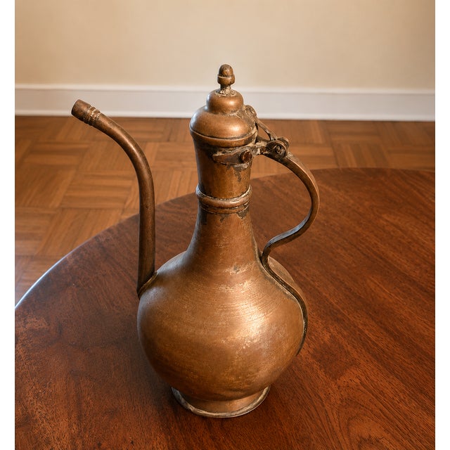 Substantial antique Turkish hand-hammered brass ewer with a graceful elongated spout, hinged domed lid, and curved handle....