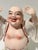 This vintage porcelain Laughing Buddha figurine features a joyful expression, raised arms, exposed belly, and flowing robe...