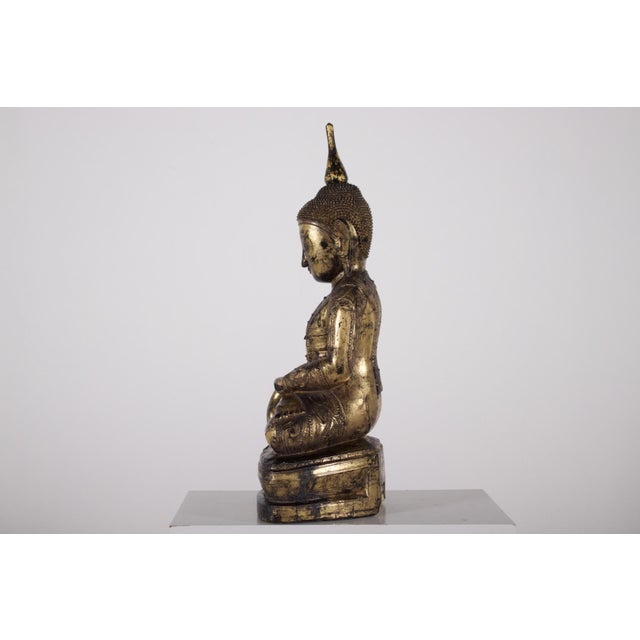 A carved wooden buddhist figure from the shan state, lacquered and gilded. The strongly modeled face and richly worked...