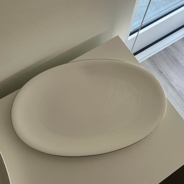 Elevate your table service with this stunning 16-inch oval serving platter from the Nikko "Deva" collection. Known for its...