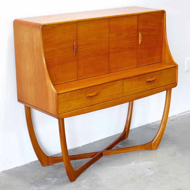This tall teak sideboard or liquor cabinet was designed by Val Rossi for Beithcraft Furniture of Scotland as part of their...