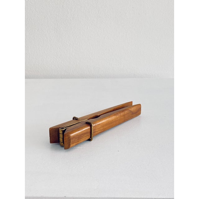 A wonderful nutcracker shaped like a clothespin. The wood is likely walnut. The hardware is made of brass.
