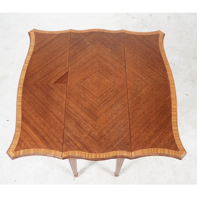 A graceful and highly functional English Hepplewhite style mahogany Pembroke table, dating to approximately 1920–1940, and...