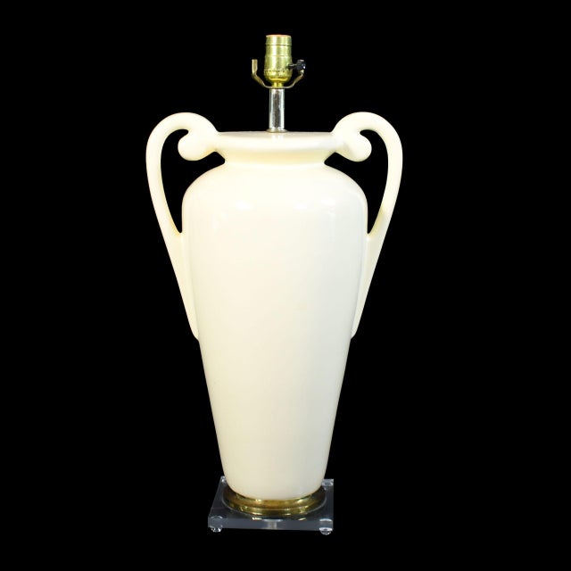A pair of ceramic trophy-form table lamps raised on clear lucite bases — a playful mix of classical shape and modern...