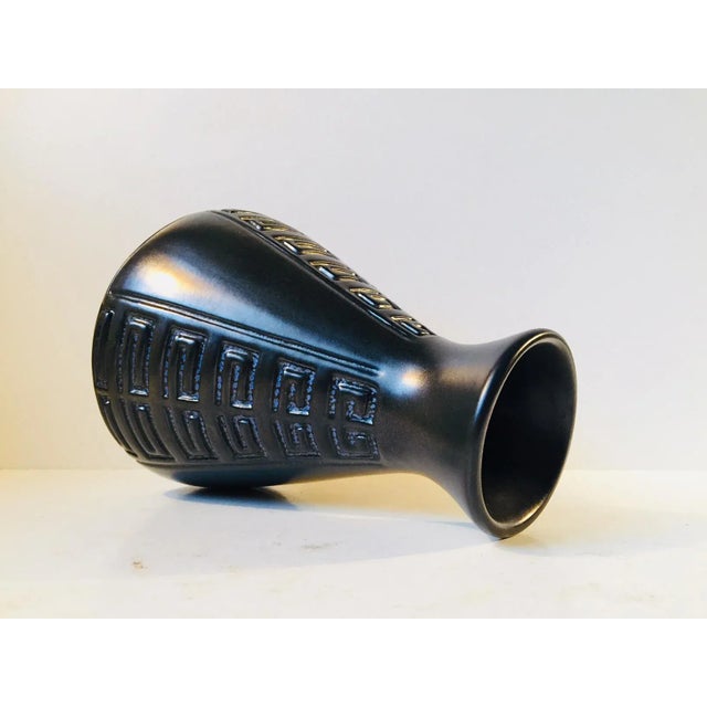 This Danish studio pottery vase with geometric patterns is inlaid with blue glaze. It was designed and manufactured by...