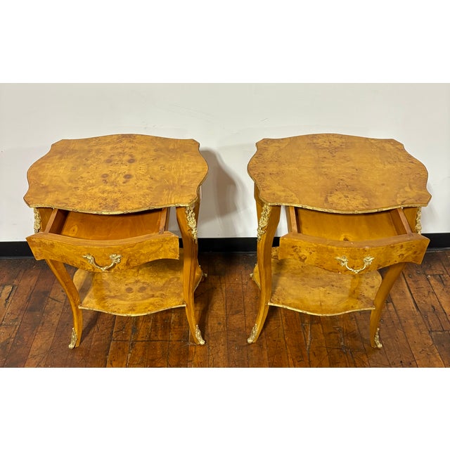 Striking pair of French XV-Style burled wood side tables. Each featuring curved cabriole legs, a single drawer to top and...