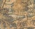 A French verdure tapestry depicting a deep woodland glade in a soft, harmonious palette of sage, moss, ochre and faded...