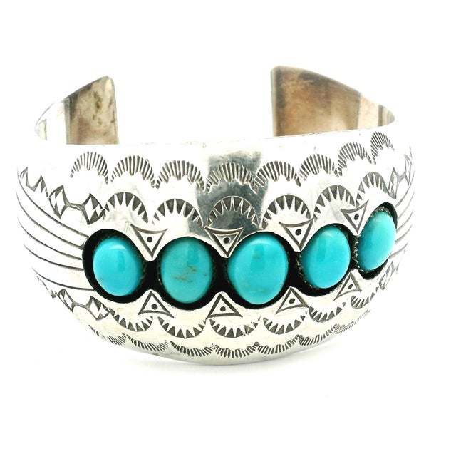 A bold vintage Navajo cuff bracelet in sterling silver, signed P. Benally, featuring five vibrant turquoise cabochons...