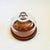 A vintage glass cloche. The top is made of heavy glass with an integrally formed handle sitting on a circular teak base. A...