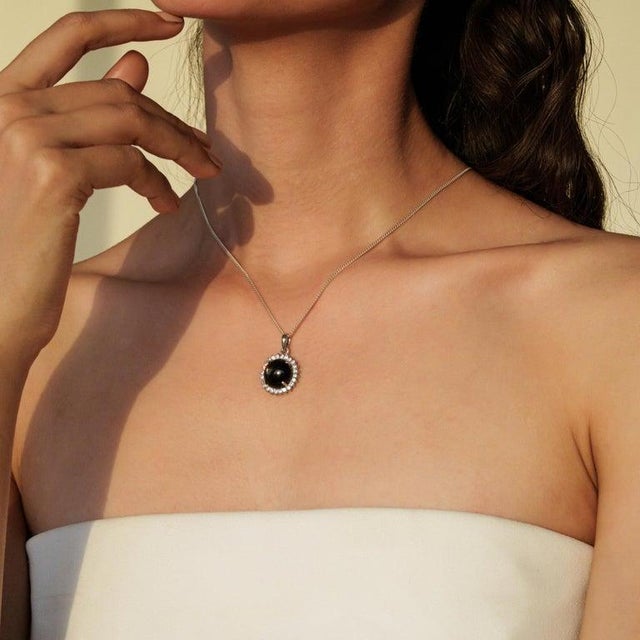 Crafted in 925 sterling silver, this antique-inspired pendant showcases a captivating 3.95 carat Black Star gemstone in a...