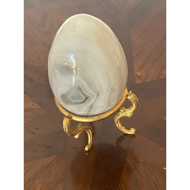 Easter egg on gold tone stand , carved and polished gray agate stone .