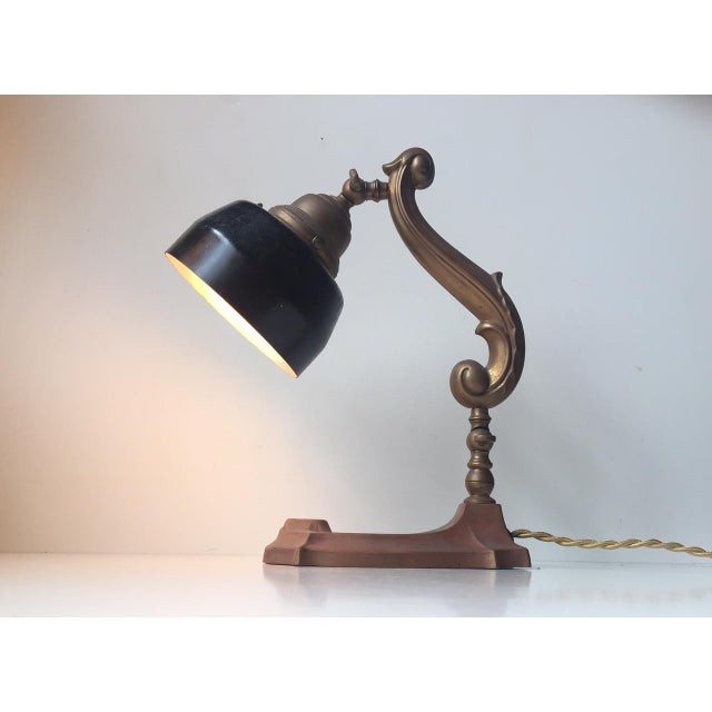 - Ornate Danish desk lamp produced in the 1920s - Features frame and base of patinated copper and brass - Black steel...